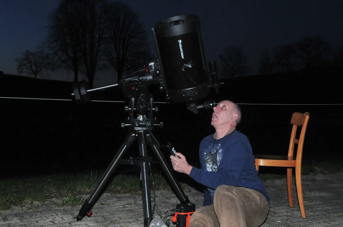 Man sieht einen Hobby-Astronomen, der sein Teleskop einrichtet.